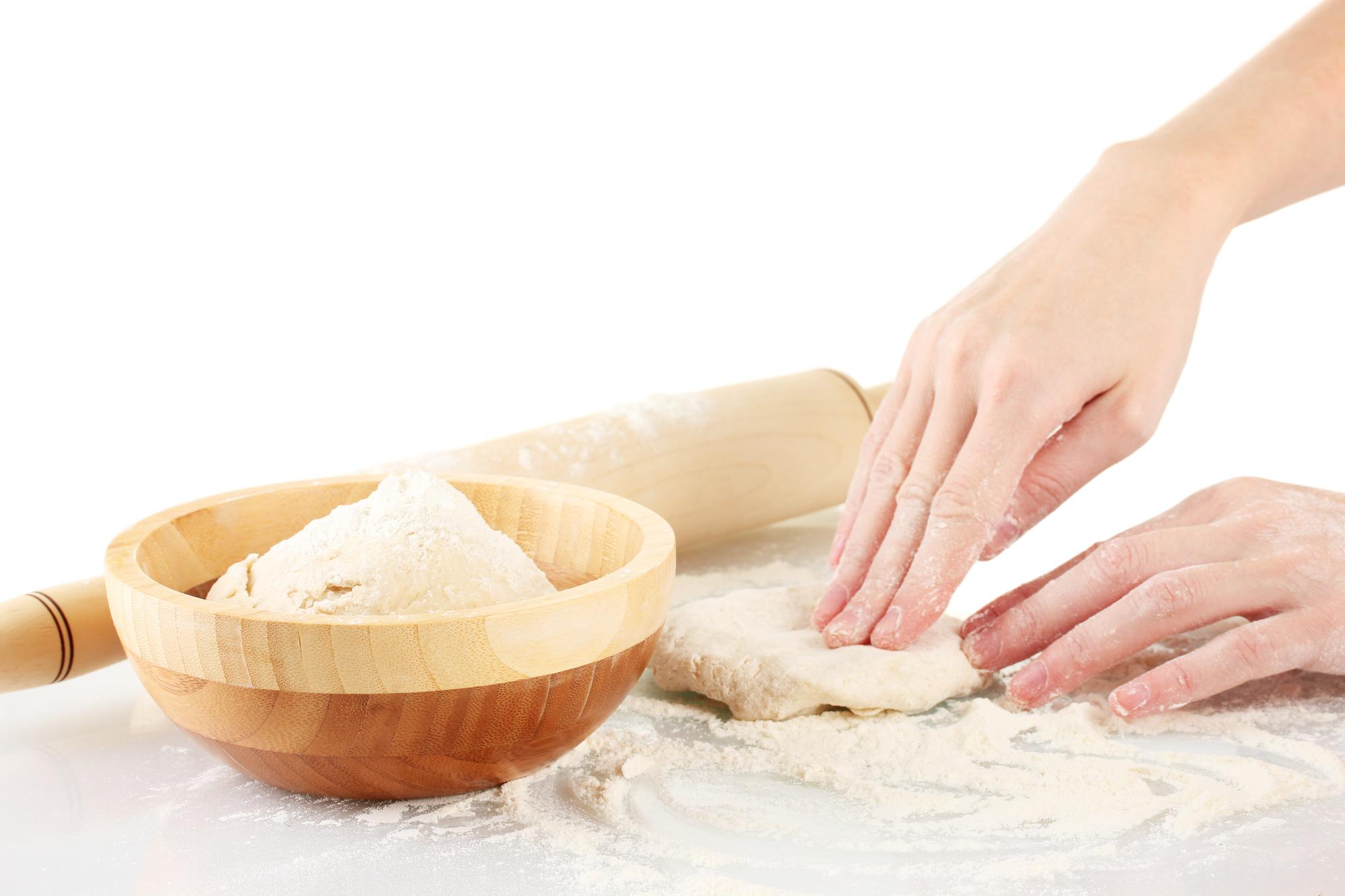 Dettaglio di mani che impastano una focaccia